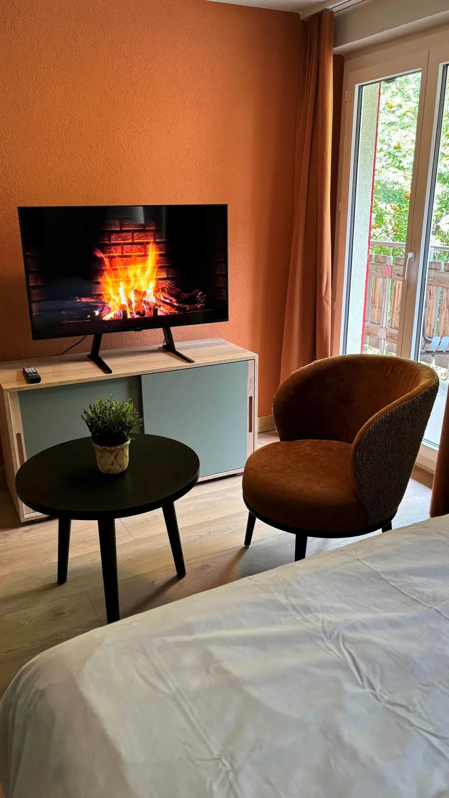 Wohnzimmer mit Smart-TV und Balkonzugang