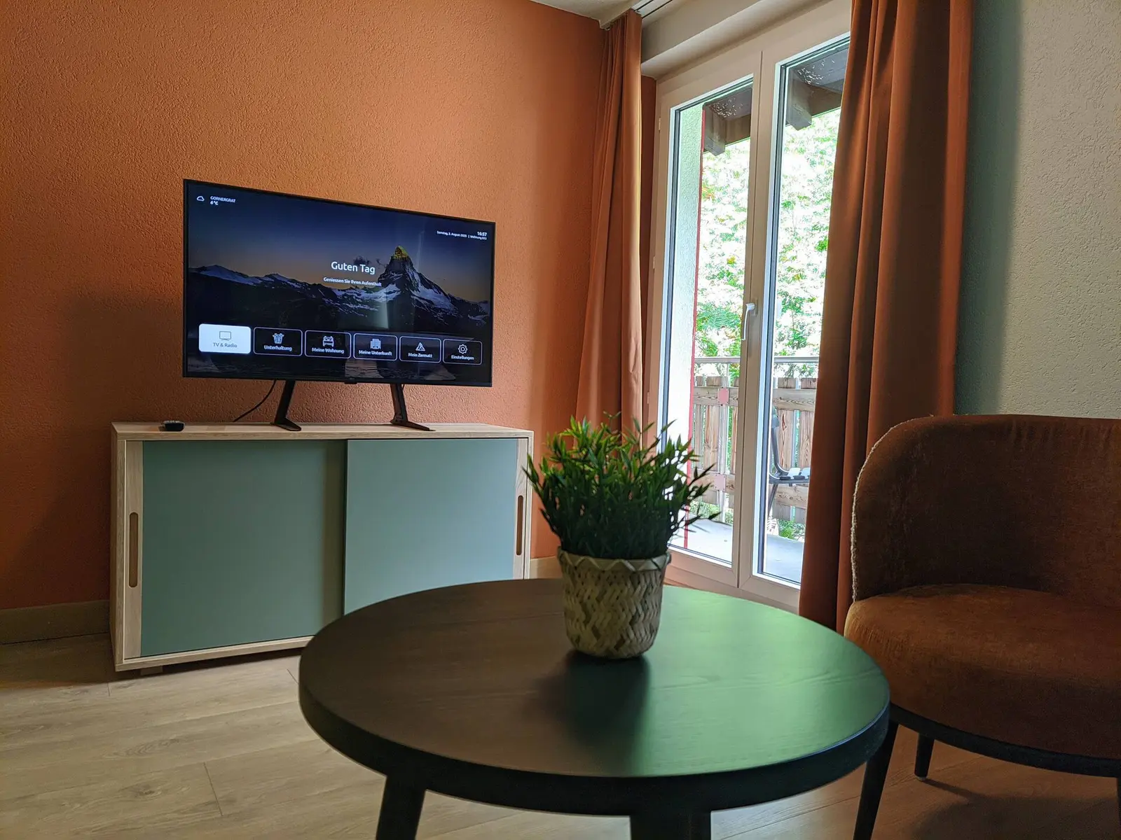 Wohnzimmer mit Smart-TV und Balkonzugang